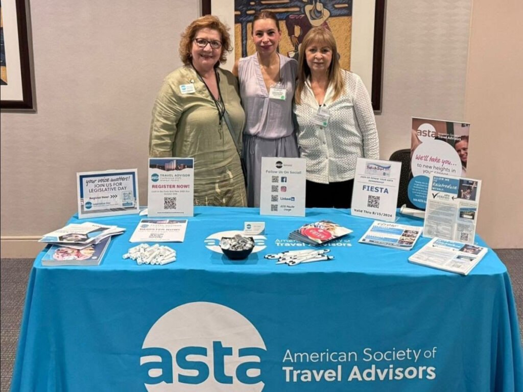 a group of women standing next to a table with a table with signs ASTA