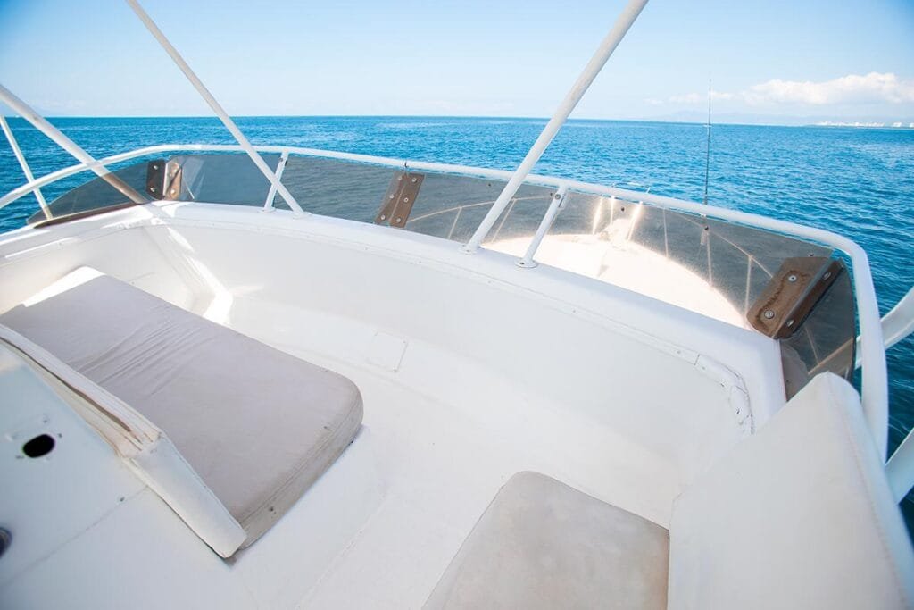 Detalle del asoleadero en proa con colchonetas blancas.