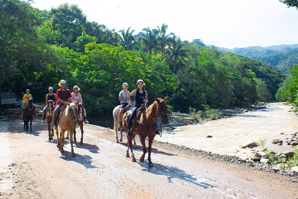 Tour de Caballos en Puerto Vallarta: Aventura en la Sierra Madre 2 Turistas descansando cerca de la refrescante cascada El Salto al finalizar el trayecto a caballo.