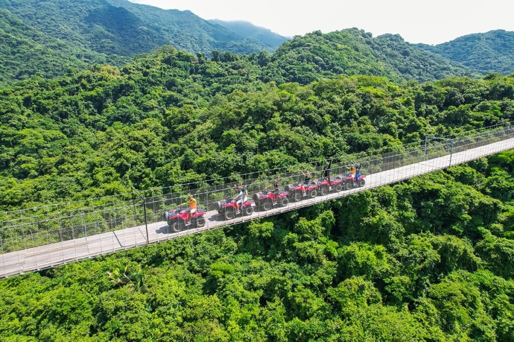 Grupo de amigos felices y saludando desde sus cuatrimotos mientras cruzan el inmenso Jorullo Bridge.