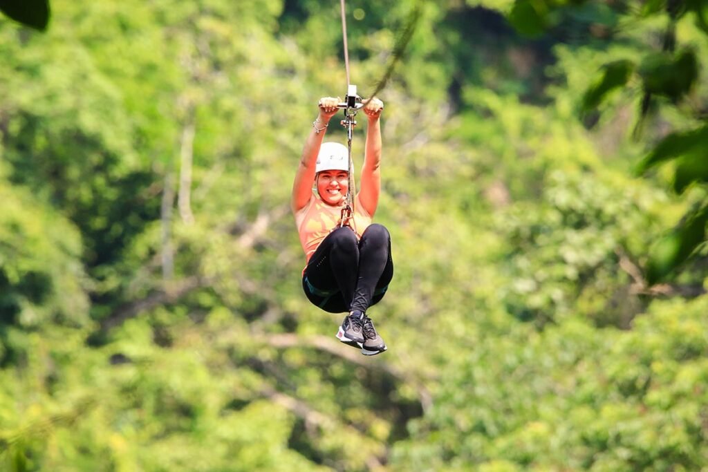 Jorullo Bridge RZR Zip Line 11 Tirolesas 3 Mujer sonriendo mientras vuela a toda velocidad en las emocionantes tirolesas en Puerto Vallarta sobre el río Cuale.