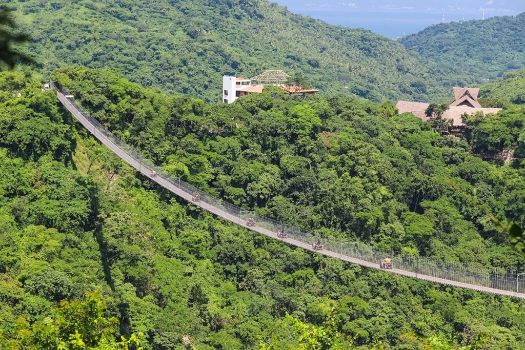 Vista distante del Jorullo Bridge, el puente colgante vehicular más largo del mundo, con cuatrimotos cruzándolo sobre el cañón.