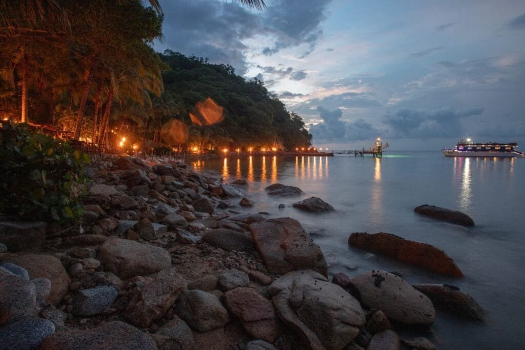 Entrada a Las Caletas iluminada con antorchas al anochecer.