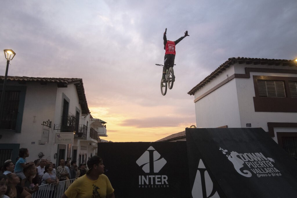 Acrobacia aérea de ciclismo freestyle durante la exhibición de Best Trick en Puerto Vallarta al atardecer frente a la multitud.