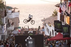 Espectacular salto de ciclismo de montaña extremo en el Downhill Puerto Vallarta 2026 con la Bahía de Banderas y el Malecón al fondo.