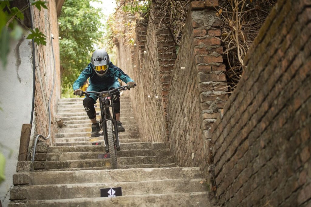 Competidor de downhill bajando por las icónicas escalinatas de piedra en el centro histórico de Puerto Vallarta durante la carrera urbana.