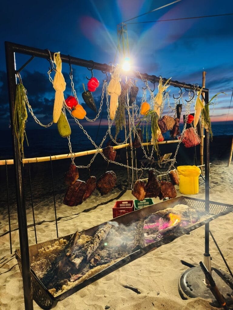 Vallarta BBQ Experience 2026: El festival que encendió la bahía 11 Escena nocturna de carne asándose al fuego bajo las estrellas.