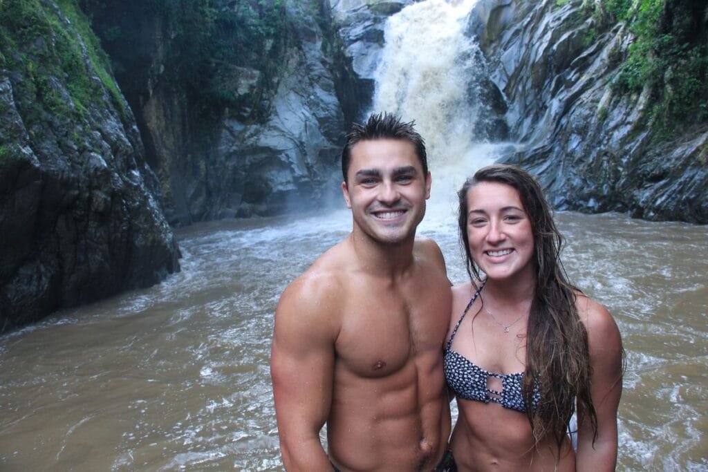 Pareja sonriendo frente a la potente caída de la Cascada Yelapa & Majahuitas Beach BBQ.