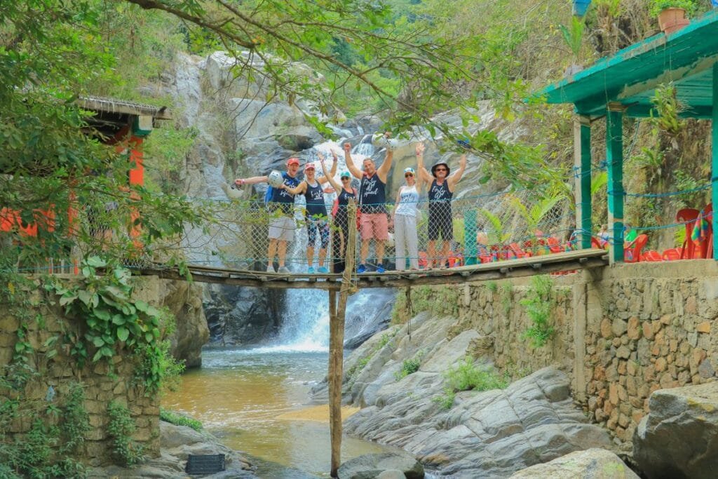 Grupo de turistas en el puente de madera con la Cascada Yelapa & Majahuitas Beach BBQ al fondo.
