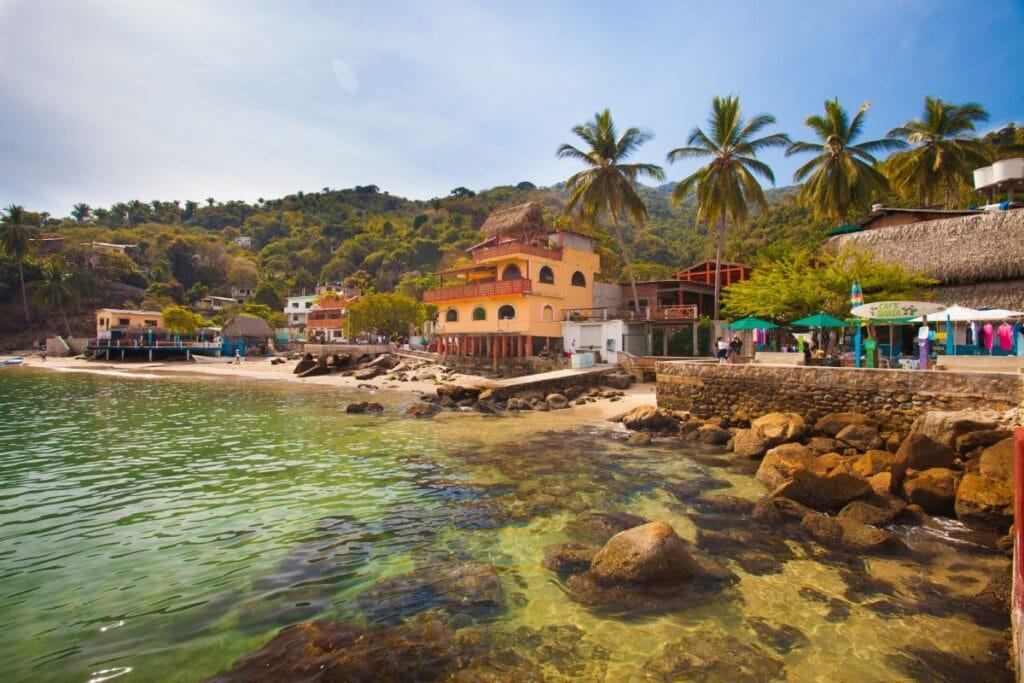 Pueblo de Yelapa con palmeras y aguas cristalinas en la orilla.