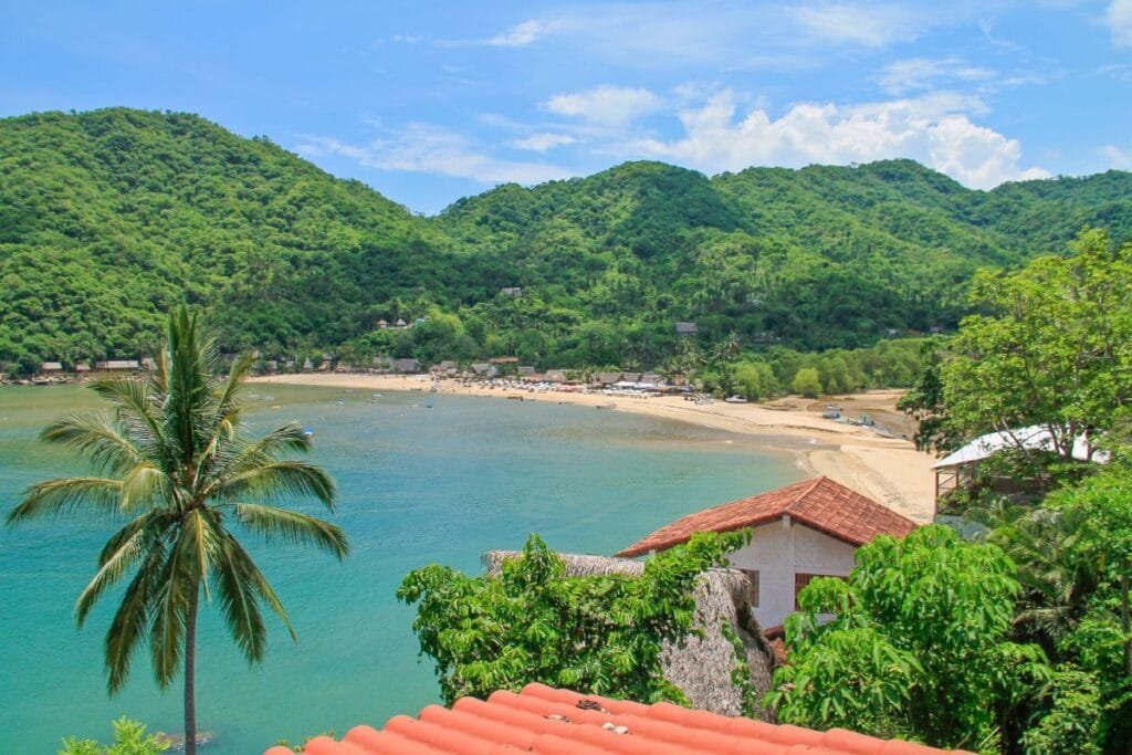 Vista panorámica de la bahía de Yelapa rodeada de montañas verdes desde un ángulo elevado.