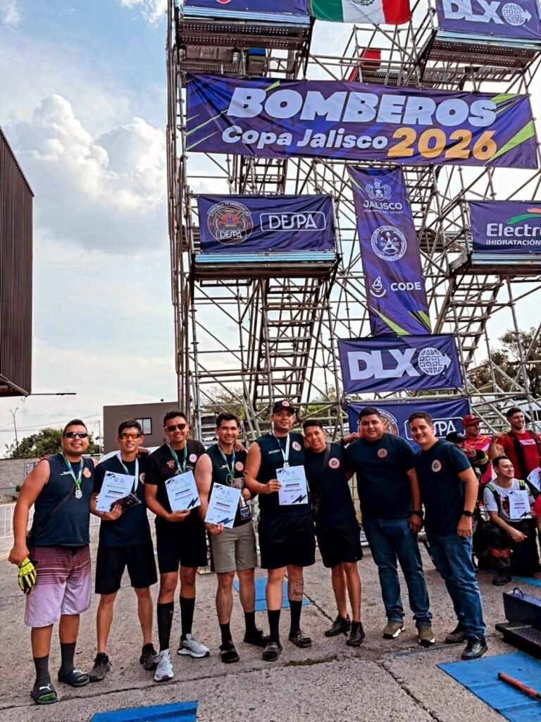 Bomberos Puerto Vallarta Triunfan en Copa Jalisco 2026 3 Delegación completa de Bomberos Puerto Vallarta posando frente a la torre de maniobras y pancarta oficial del evento deportivo estatal 2026