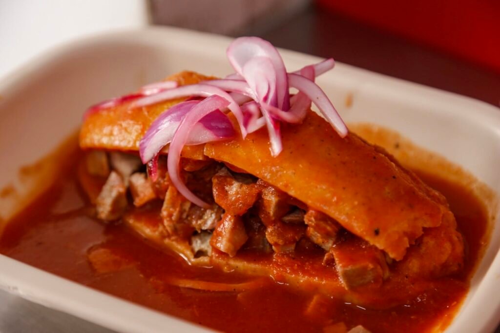 Turismo MICE en Guadalajara: Auge 2026 2 Tradicional torta ahogada bañada en salsa con cebolla morada, un icono de la gastronomía de Guadalajara y Jalisco.