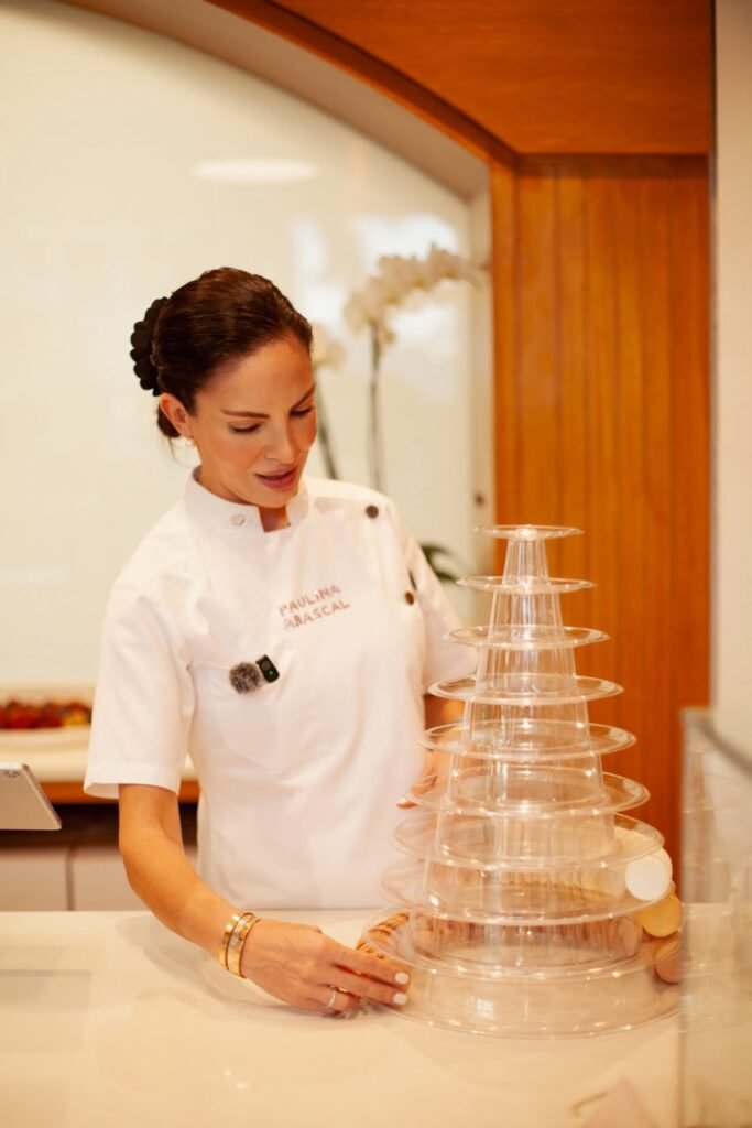 La chef repostera Paulina Abascal monta y revisa una elegante torre de macarons durante el cóctel inaugural de Natisa en Puerto Vallarta.