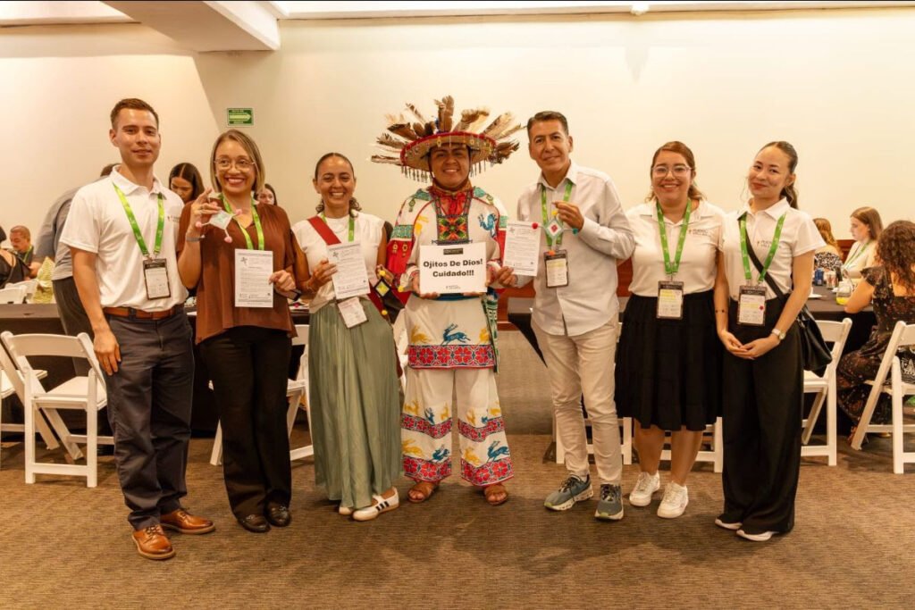 Grupo de meeting planners sonriendo junto a un representante de la cultura wixárika sosteniendo artesanías.