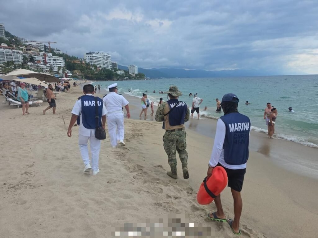 Operación Salvavidas Verano 2026: Éxito Total en Playas 5 Patrulla combinada de personal naval y salvavidas caminando a la orilla del mar entre turistas nadando en aguas tranquilas de Vallarta.